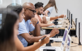 Students seated at laptops in a classroom during a cybersecurity training session